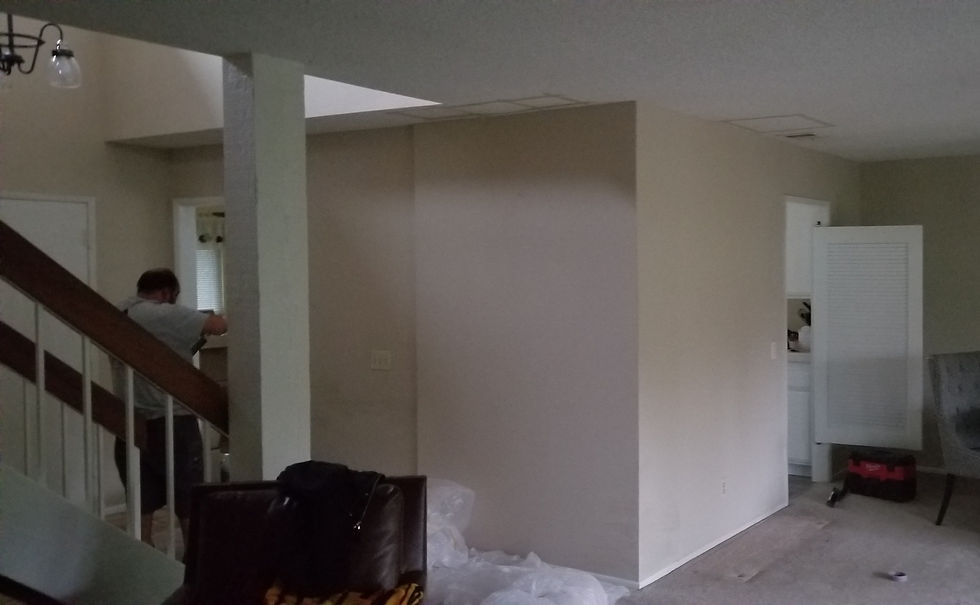 Before remodel — closed-off living area with a blank wall hiding the kitchen, beside the staircase
