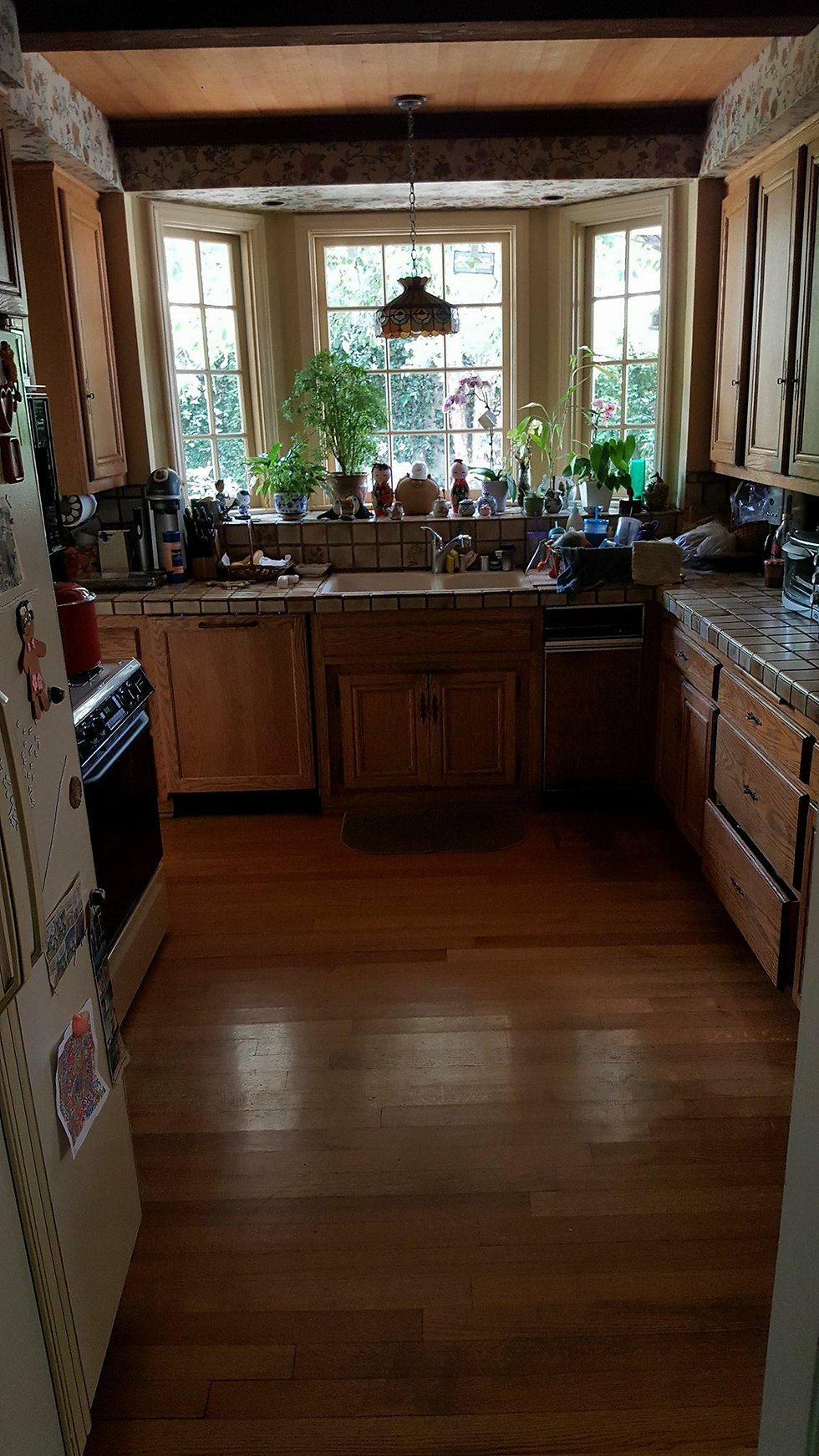 Citrus kitchen before remodel — dated oak cabinets, tile counters and floral wallpaper
