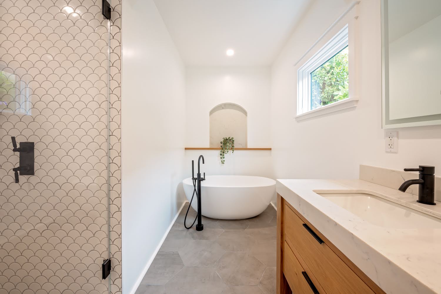 Lillian Master Bathroom — view past the scallop-tile shower and wood vanity to the freestanding tub