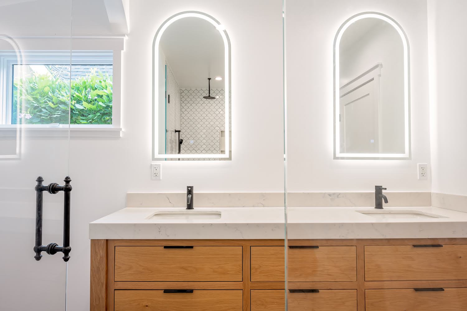 Lillian Master Bathroom — double wood vanity with arched backlit mirrors and black faucets