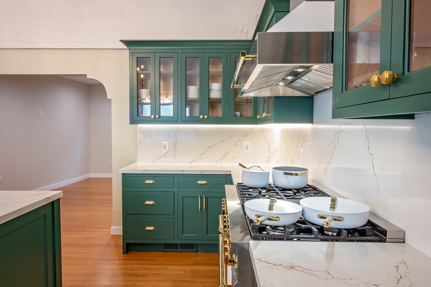 Lillian Kitchen Remodel — range detail with white cookware, stainless hood, marble backsplash and glass-front cabinets