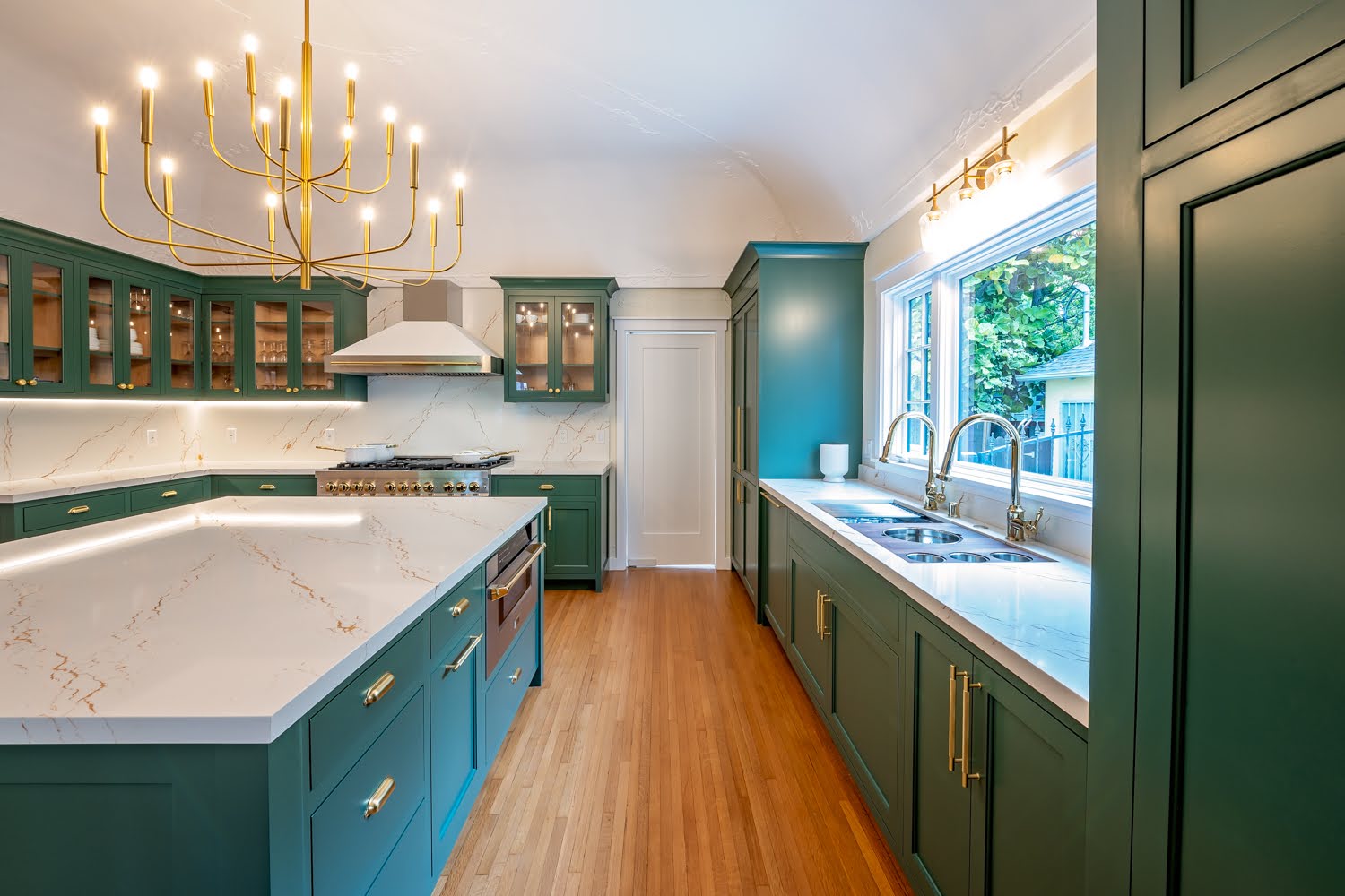 Lillian Kitchen Remodel — view along the island to the sink run under large windows with brass faucets